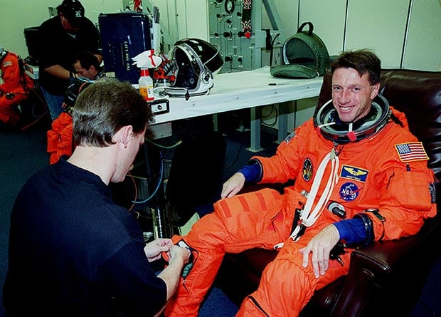 In the suit-up room at Kennedy Space Center, Michael Foale smiles as a suit technician helps him don his launch and entry suit before liftoff on the STS-103 mission in December 1999. Photo: NASA