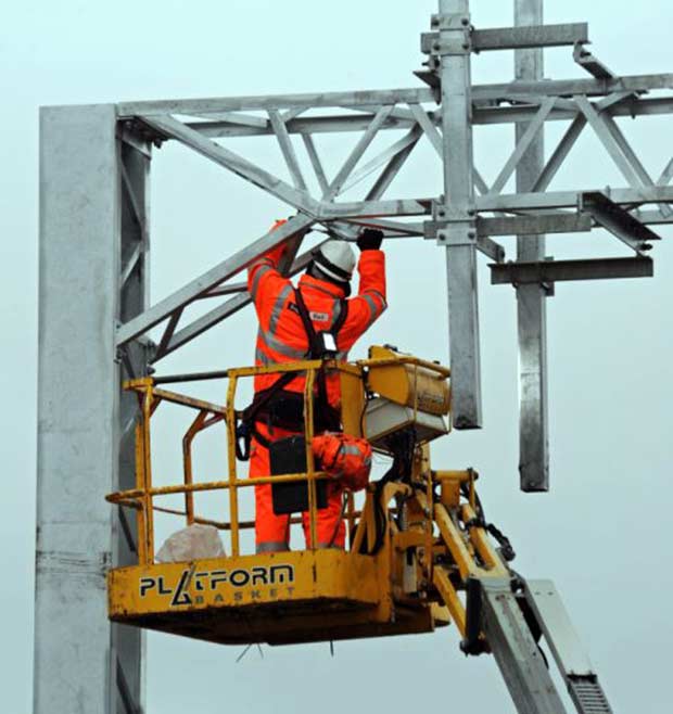 An engineer works on overhead electric cabling for line electrification. Photo: Network Rail
