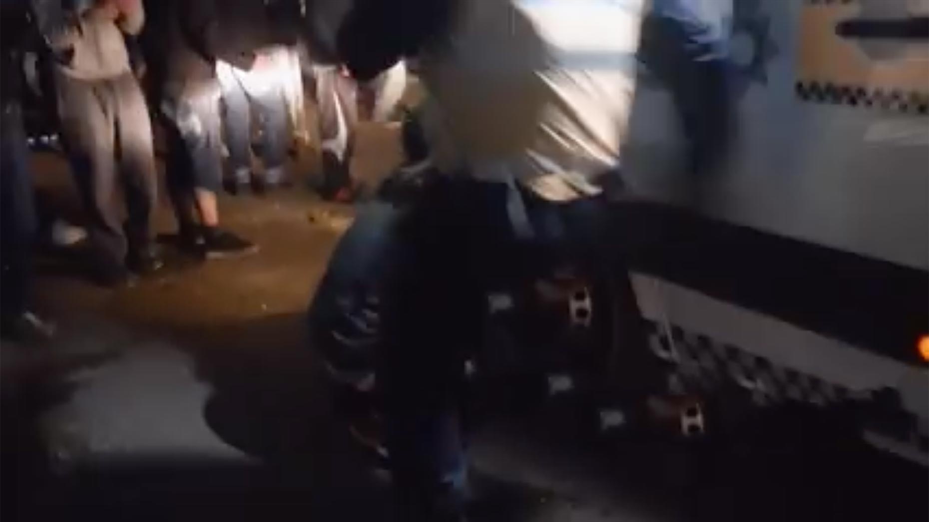 Back at the riot van where the man is deflating a tyre, an officer swoops in and appears to kick the man. Screenshot: Chris Shaw